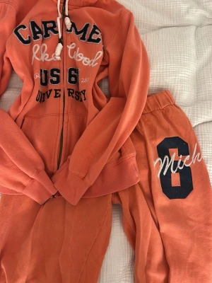 Coral mjukisett - Mysig orange mjukisdress med huva och dragkedja. Köpte setet på second hand och då var flecken på tröjan redan där. Säljer för att jag inte använder det. St Xs/S. Setter är från Tindra💛