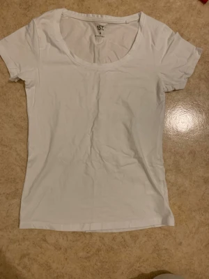 Vit basic t-shirt M - En enkel vit t-shirt med rund halsringning och korta ärmar. Tillverkad i mjuk bomull som känns skön mot huden. Perfekt att matcha med jeans eller shorts för en clean och avslappnad stil.