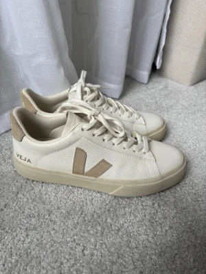 Vita Veja sneakers med beige detaljer - Snygga vita sneakers från Veja. Skorna har klassisk låg profil, vita snören. Perfekta för dig som gillar stilrena och trendiga sneakers med en clean look. Använda en gång, ny pis 1699kr