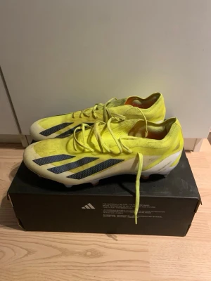 Gula Adidas fotbollsskor crazyfast - Snygga fotbollsskor från Adidas i en skarp gul färg med klassiska svarta ränder på sidorna. Skorna har låg profil, snörning och är tillverkade i syntetmaterial för bra grepp och känsla på planen. Dubbarna är till för gräs. Säljer för dem är för små. Hör av vid pris och funderingar 