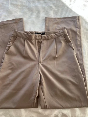 Beiga kostymbyxor  - Beiga/bruna kostymbyxor. Köpta på vinted men passade ej. Lite noppriga men annars fina.