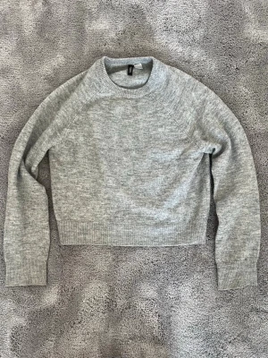 Ljusgrå stickad tröja från H&M - Mysig ljusgrå stickad tröja från H&M i storlek XS. Tröjan har rund halsringning, långa ärmar och ribbade muddar vid ärmslut och nederkant. Perfekt för lager på lager och enkel att matcha med olika outfits.