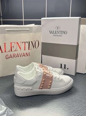 Valentino Rockstud vita sneakers - Snygga vita sneakers från Valentino Garavani med ljusrosa band och ikoniska nitar över vristen. Alla storlekar 35-39
