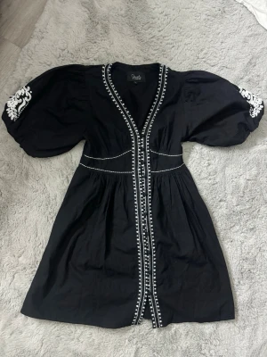 Svart kortklänning med broderi - skickar idag  - En jättefin svart broderad klänning från indiska. Köpt innan sommaren och den säljs inte längre. Prislappen är borta men den är bara provat på och har tyvärr inte kommit till användning. Normal i storleken och inga skavanker eller något slitage alls🩷🩷 Originalpris ligger på 1299kr  