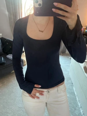 Mörkblå långärmad topp - Snygg mörkblå långärmad topp med fyrkantig ringning. Toppen har en slim passform och är tillverkad i ett mjukt, stretchigt material som sitter skönt på kroppen. Perfekt att styla med både jeans och kjol.