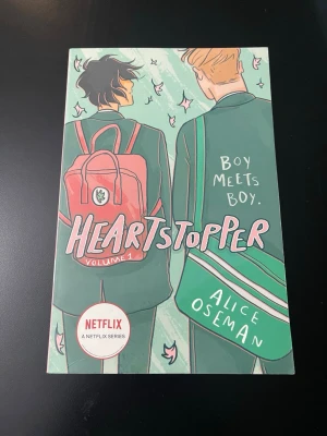 Heartstopper 1 - Heartstopper Vol 1 är en grafisk roman med färgstarkt illustrerat omslag i grönt, rosa och vitt. Boken handlar om två killar som möts, blir vänner och förälskar sig. Perfekt för dig som gillar romantik och ungdomsberättelser. Inspirerade illustrationer och modern design.