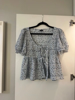 Blommig blus med puffärm och knyt - Superfin blus med blått och vitt blommönster. Puffiga korta ärmar och söt knytning framtill. Perfekt för en somrig outfit🩵 använd få gånger!