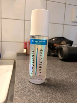 Brun utan sol! Tanologist Express Tan Self Tan Water - Tanologist Express Tan Self Tan Water i medium är en genomskinlig brun-utan-sol-vätska i plastflaska med vitt lock. Produkten ger en naturlig solkysst look och är enkel att applicera utan att kladda. Perfekt för dig som vill ha en jämn och fräsch bränna.