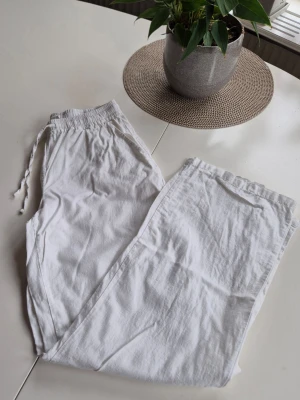 Vita linnebyxor med dragsko - * Linnebyxor från Madlady med resår och dragsko i midjan.  * Byxorna har fickor i sidorna och raka ben. * Märkt XS. * Innerbensmått ca 75 cm. * Ca 25 cm breda i bensluten.  Förstora bilderna då de ingår I beskrivningen.  Djur och rökfritt hem.  Se gärna mina övriga annonser. 