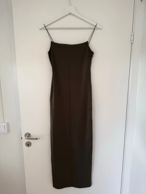 Grön klänning - Grön långklänning med tunna axelband i ett mjukt och följsamt material.  Klänningen har tajt passform och kan upplevas något liten i storleken. Tyvärr framgår inte riktigt den fina olivgröna färgen på bilderna.  