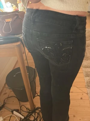 Svarta jeans med strassdetaljer - Säljer ett par svarta jeans med utsvängda ben och snygga strassdetaljer på bakfickan. Från Gina och är uppsprätta längst ner!🥰🥰
