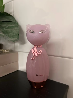 Meow! EDP Katy Perry - Säljer en söt parfymflaska från Katy Perry, Meow!, formad som en katt i ljusrosa glas med metallicrosa detaljer och gnistrande ögon. Flaskan har ett dekorativt M-halsband och glänsande botten. Helt ny! Aldrig använd.