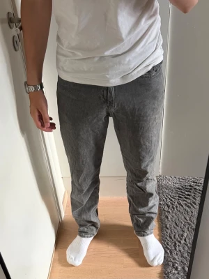 Grå raka jeans från H&M - Säljer ett par grå jeans med rak passform och klassisk femficksdesign. Jeansen har en tvättad finish som ger en avslappnad vibe och är tillverkade i bomull. Perfekta till en enkel t-shirt eller hoodie.