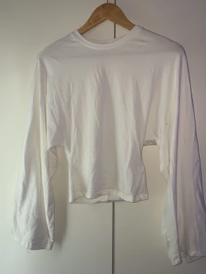Vit långärmad tajt i midjan  topp - Säljer en enkel och stilren vit långärmad topp med najs passform. Toppen har rund halsringning och är tillverkad i ett mjukt material som känns skönt mot huden. Perfekt att matcha med låga jeans eller kjol.