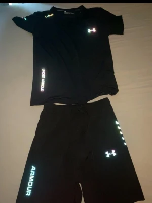 Svart träningsset från Under Armour - Säljer mitt Under Armour set som består av T-shirt och shorts i storlek M.