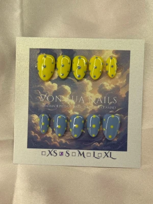 Yellow/BlueDot (S);ExtraShortAlmond  - Unika handgjorda press-on naglar i en extra kort mandelform. Översta raden är gula med blå prickar, medan nedersta raden är blå med gula prickar. Handgjorda och riktigt trendiga, perfekta för dig som vill sticka ut med färg och kreativ design.S: 15 mm, 11,5 mm, 12 mm, 11 mm, 9 mm 