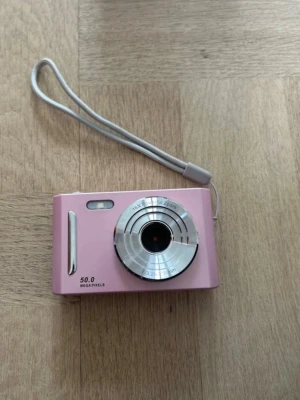 Digital kamera - Säljer en digitalkamera i en supersöt puderrosa färg med silverknappar. Perfekt för att få till de där härliga retrobilderna med äkta Y2K-känsla! Det är bara att ladda och börja fota direkt. Den laddas med vanlig USB C som ingår. Det ingår även ett minneskort med 32GB. Skriv om du har frågor!  Detta ingår i paketet: 1x Rosa CCD-digitalkamera 1x 32GB Minneskort 1x Vit USB C -laddkabel 1x Grå handledsrem