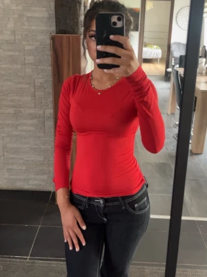 Röd långärmad tight tröja - Säljer en röd långärmad tröja med tight passform. Klänningen har enkel design utan synliga detaljer och är perfekt för dig som gillar stilrena plagg. 