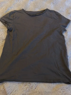 Mörkgrå basic t-shirt i bomull - En enkel och stilren mörkgrå t-shirt med rund hals och korta ärmar. Tillverkad i mjuk bomull som känns skön mot huden. Perfekt att matcha med jeans eller shorts för en clean look.