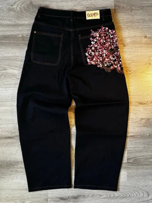Derschütze “Blossom” Indigo Raw Denim Jeans - Strl. 32 - Hej! Jag säljer ett par super snygga schyze cherry blossom denim jeans i storlek 32 Baggy design som sitter löst på benen för en snygg streetwear design Cherry blossom design på baksidan ficka Modell: DSE-5087M-3 Kommer från ett djur och rökfritt hem Skickas samma dag! 