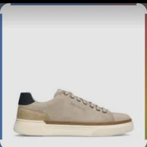 Beige sneakers med mockadetaljer - Stilrena beige sneakers i mocka med vita sulor och mörk detalj vid hälen. Klassisk låg modell med snörning och diskret design som passar till det mesta. Perfekt för dig som gillar en clean och enkel look.