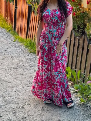 Blommig långklänning i rosa och turkos - One Size! Passar alla storlekar. Snygg långklänning med blommigt mönster i rosa och turkosa toner. Klänningen har korta ärmar, markerad midja och rund halsringning. Perfekt för varma dagar och somriga kvällar. Lätt och luftig känsla.