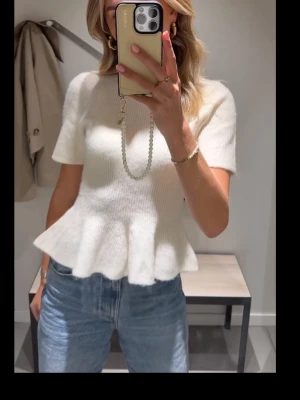 Beige stickad topp med volangkant - !Säljer pga jag aldrig använt sen jag köpte ! Supersöt beige stickad topp med korta ärmar och volangkant nedtill. Toppen har rund halsringning och är lätt croppad, vilket ger en modern och trendig look. Perfekt att styla med jeans eller kjol för en fräsch outfit. Storleken e S men den är stretchig så passsar även Xs-M