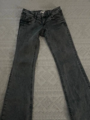 Gråa slim fit jeans med tvättad look - Säljer ett par gråa flared fit jeans med tvättad look och klassiska fem fickor. Jeansen har normal midja och raka ben. Perfekta för dig som gillar en avslappnad men ändå trendig stil.
