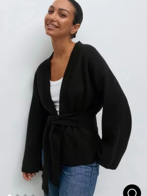 Svart stickad kimono med knytskärp - Svart stickad kimono från Gina Tricot med breda ärmar och knytskärp i midjan. Helt slutsåld!