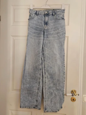 Ljusblåa wide leg jeans - Säljer ett par ljusblåa jeans med wide leg-modell och hög midja. Jeansen har klassisk femficksdesign och är tillverkade i denim med tvättad look. Perfekta för en avslappnad och trendig stil.