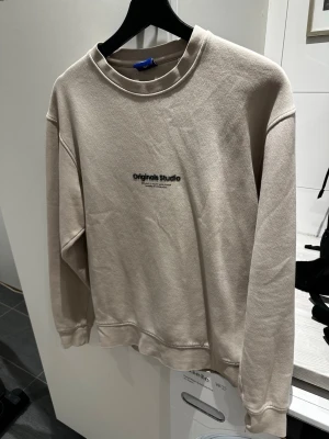 Beige sweatshirt från Jack & Jones - Snygg beige sweatshirt från Jack & Jones Originals Studio med diskret svart text på bröstet. Storlek XS men passar också S. Tröjan har rund halsringning, långa ärmar och ribbade muddar. Perfekt för en avslappnad och trendig stil. Mjuk bomullskvalitet för extra komfort. Skriv över det minsta lilla eller över den minsta funderingen!🔥🔥