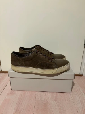 Lanvin skor - Snygga bruna sneakers från Lanvin. Ovandel i mocka och tåparti i blankt läder. Skorna har bruna skosnören och en vit, något gulnad sula. Perfekta för dig som gillar en stilren och klassisk look. 