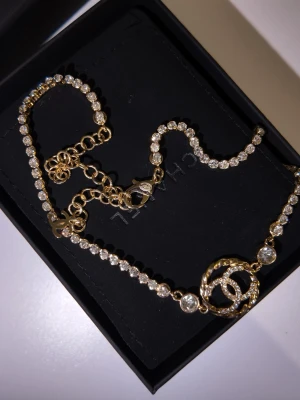 Chanel halsband med pärlor och CC-logo - Lyxigt halsband från Chanel med gnistrande pärlor längs hela kedjan och den ikoniska CC-logotypen i guldtonad metall. Logotypen är dekorerad med små stenar och halsbandet har justerbar längd med elegant lås. Perfekt för dig som vill sticka ut.With box💝