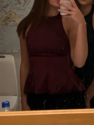 Vinröd satin topp - Snygg vinröd satin topp. Toppen har en figurnära passform upptill och volang nertill som ger en trendig siluett. Perfekt att styla med jeans eller kjol för en cool look. Använd 1 gång ❤️