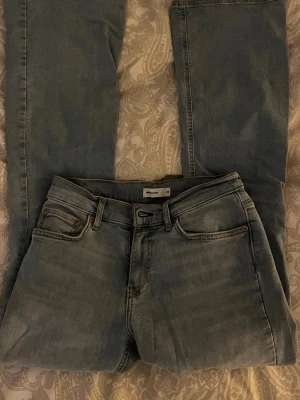 Ljusblå bootcut jeans från Gina Tricot - Säljer ett par ljusblå bootcut jeans från Gina Tricot. Jeansen har klassisk femficksmodell, bälteshällor och dragkedja med knapp. Materialet är denim i bomull och passformen är utsvängd nedtill för en trendig look.