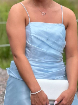 Ljusblå långklänning med tunna axelband -  ljusblå långklänning med tunna axelband . Klänningen har diskreta små pärldetaljer bal.  Är i storlek L men är liten i storlek så passar mig som jag M. Billigare vid snabb affär. 