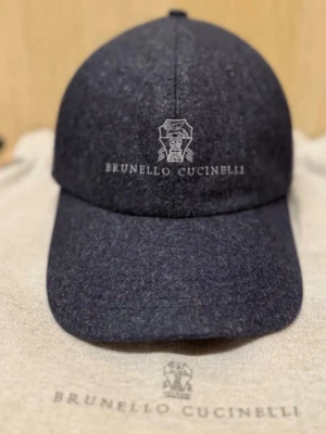 Mörkgrå keps från Brunello Cucinelli - Snygg mörkgrå keps från Brunello Cucinelli med broderad logotyp och text framtill. Klassisk böjd skärm och justerbar passform. Tillverkad i ett mjukt, ull-liknande material som ger en exklusiv känsla. Perfekt accessoar för en stilren look.