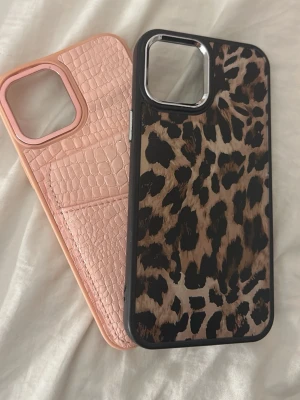 Två trendiga mobilskal med mönster - Säljer två snygga mobilskal – ett i ljusrosa med krokodilstruktur och kortfack, och ett med leopardmönster och svarta kanter. Perfekta för dig som vill ha ett unikt och stilrent skydd till mobilen. iPhone 12 Pro Max