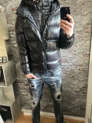 Polo rl jacka  - Snygg svart dunjacka från polo med glansig finish och vadderad design. Jackan har huva, dragkedja och tryckknappar framtill samt justerbara detaljer vid huvan. Perfekt för kalla vinterdagar och riktigt trendig look.