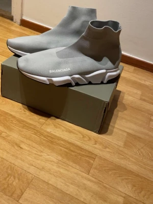 Grå Balenciaga Speed Trainer sneakers - Grå Balenciaga Speed Trainer sneakers med stickad ovandel i textil och vit chunky sula. Strumpliknande passform och diskret logga på sidan. Lätta och flexibla för en modern streetwear-look.