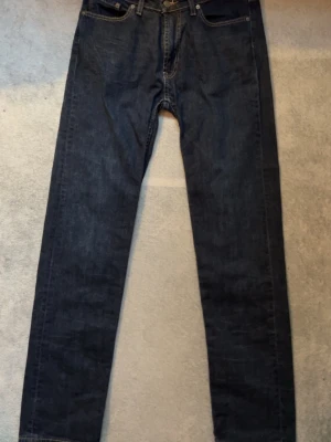 Mörkblå raka jeans från Dressman - Snygga mörkblå jeans från Dressman med klassisk femficksdesign och raka ben. Jeansen är tillverkade i denim och har en enkel, tidlös look som passar till det mesta. Perfekta för dig som gillar en clean och stilren stil.