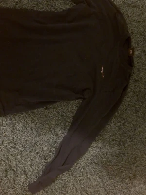 Svart långärmad tröja Tommy Jeans - En svart långärmad tröja från Tommy Jeans med rund halsringning och diskret logga broderad på bröstet. Tröjan har en enkel och clean design som passar till det mesta. Perfekt basplagg för garderoben.