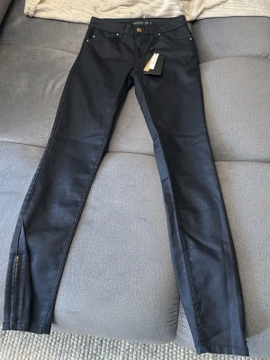 Svarta skinny jeans från Stockh LM - Snygga svarta jeans från Stockh LM. dragkedjedetaljer vid bensluten. Jeansen har en stilren look och passar bra en 