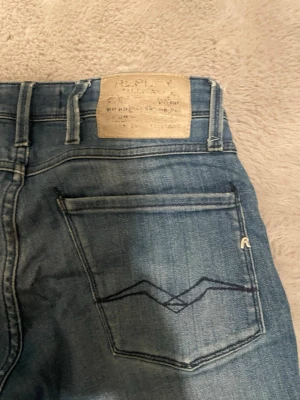 Replay blå jeans  - Snygga blå jeans från Replay med klassisk femficksdesign och broderade bakfickor. Jeansen har en ljus tvätt och raka ben. Perfekta för dig som gillar en avslappnad men trendig stil.   (Har en liten fläck på baksidan som knappt syns) midjan är 27 och längd 32