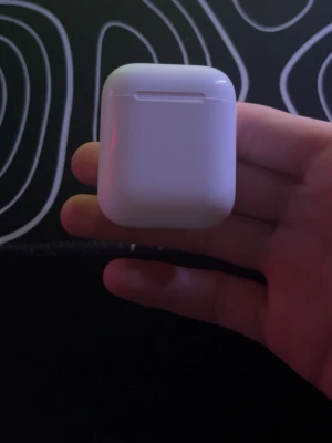 Apple laddningsetui - Trådlösa vitt laddningsetui i blank plast. Smidig och kompakt design som enkelt får plats i fickan.  anslutning till iPhone och andra Apple-enheter. Saknar aipodsen därför säljer den för någon som kanske är intresserad som har airpodsen kvar men ej laddningsetui