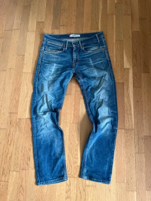 Vintage archive Levi’s jeans  - Säljer ett par klassiska blå Levi's jeans med snygga tvättade detaljer. Jeansen har fem fickor, raka ben och normal midja. Perfekta för en avslappnad och trendig look. Materialet är 100% bomull. Dem är perfekta för dig som gillar vintage archive jeans! Priset är ej hugget i sten! 