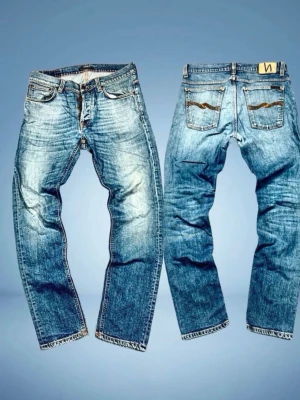 Blå jeans från Nudie Jeans Co - Säljer ett par blå jeans från Nudie Jeans med riktig fet och sliten tvätt. Jeansen har snygga detaljerade bakfickor med Nudie-logga. Perfekta för en avslappnad och trendig look. Midjan är 43. Längd, 101. Lår, 27 och benöppning, 18,5 