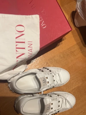 Valentino vita sneakers med nitar - Vita valentino skor med guld nitar, använt fåtal gånger, hela paketet kommer med, med låda, påse och skor. Storlek 40, lite stora på mig.