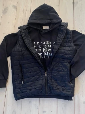 Mörkblå hoodie Maison Margiela - ‼️‼️‼️PRIS GÅR ATT DISKUTERA   Mörkblå hoodie från Maison Margiela med vit logotyp och siffertryck på bröstet. Klassisk huva med dragsko och magficka framtill. Tillverkad i mjukt bomullsmaterial, perfekt för en avslappnad och trendig look.