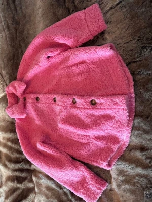 Gina Tricot rosa jacka - Rosa jacka med knappar framtill och krage. Jackan har en mjuk och fluffig textur.  Strl XS  Använd 1-2 ggr